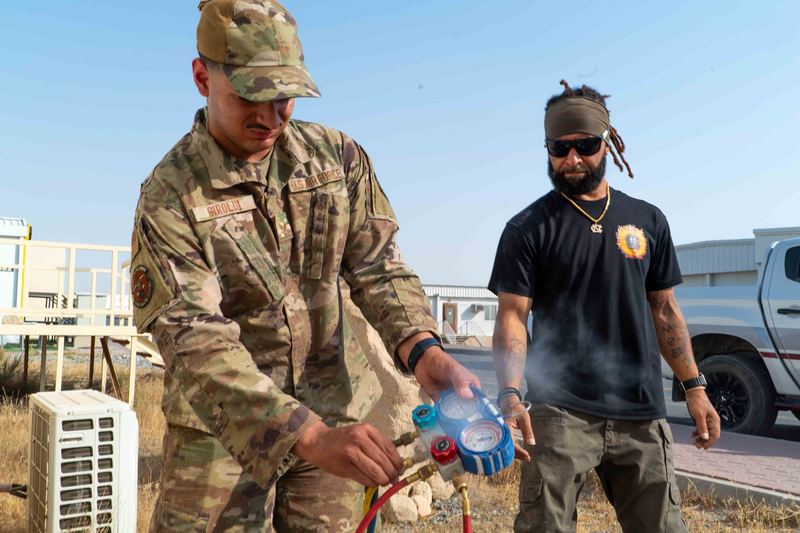 U.S. Air Force Senior Airman Gianni Giroldi, left, 386th Expeditionary Civil Engineer Squadron heating, ventilation, air conditioning and refrigeration specialist, adjusts a gauge 